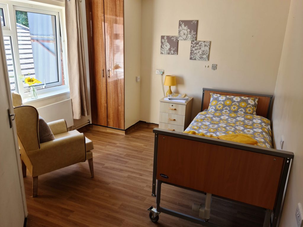 A young man and elderly woman have a heartfelt conversation in a cozy bedroom setting.