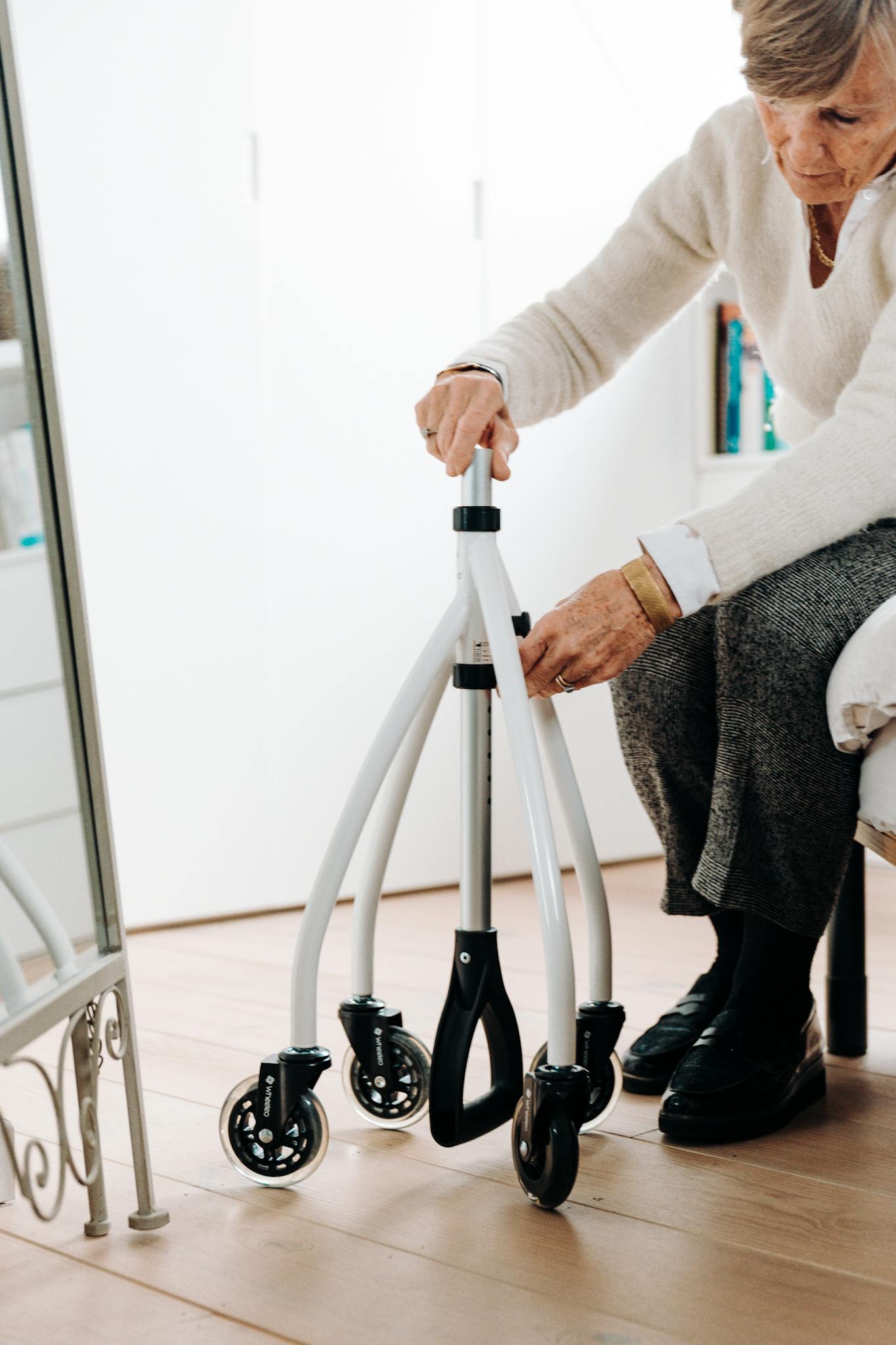 Elderly woman making adjustments to her rollator walker at home.
